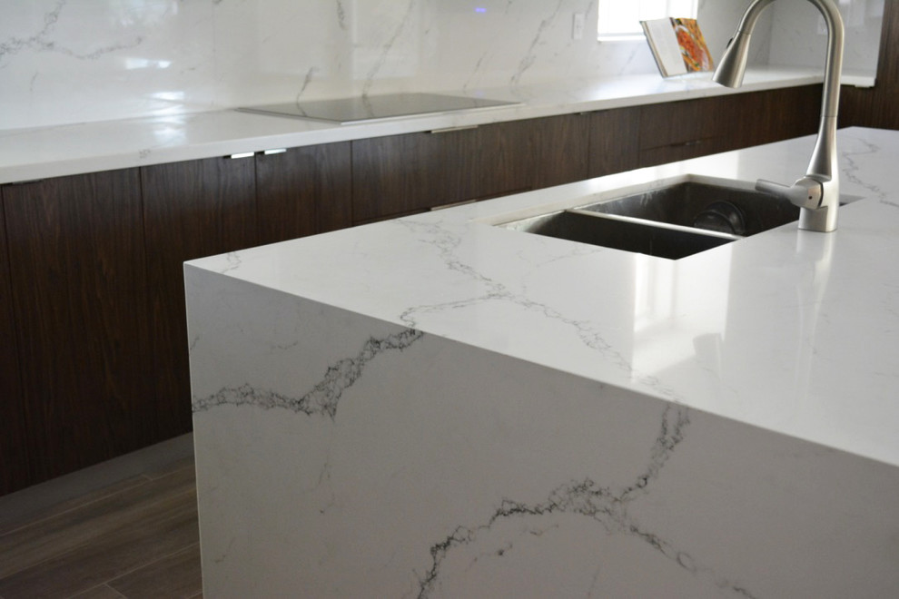 Open concept kitchen - large transitional u-shaped medium tone wood floor and brown floor open concept kitchen idea in Miami with a double-bowl sink, flat-panel cabinets, dark wood cabinets, quartzite countertops, white backsplash, marble backsplash, paneled appliances, an island and white countertops