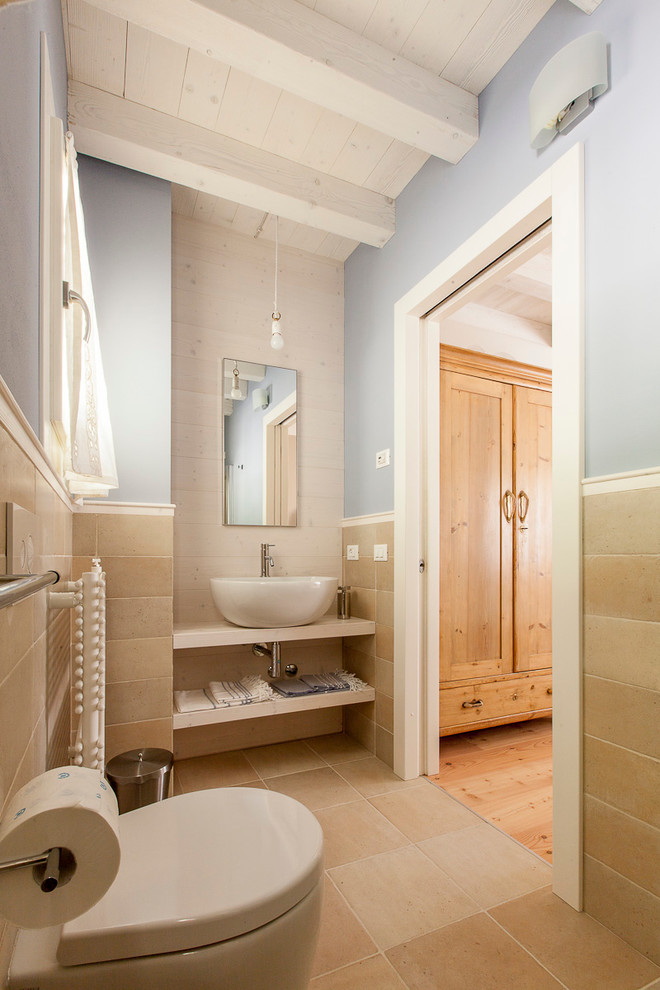 This is an example of a mid-sized traditional bathroom in Venice with open cabinets, light wood cabinets, beige tile, stone slab, a vessel sink and wood benchtops.