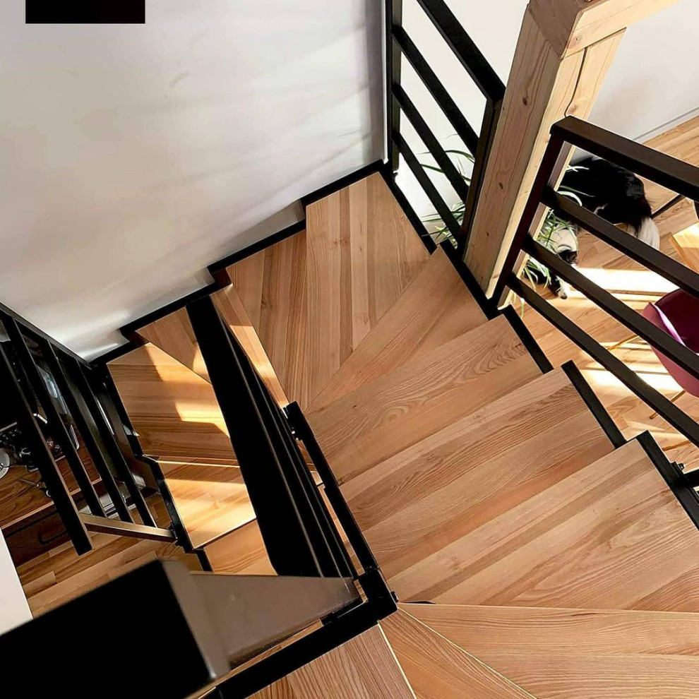 На фото: винтовая деревянная лестница среднего размера в стиле лофт с деревянными ступенями и металлическими перилами