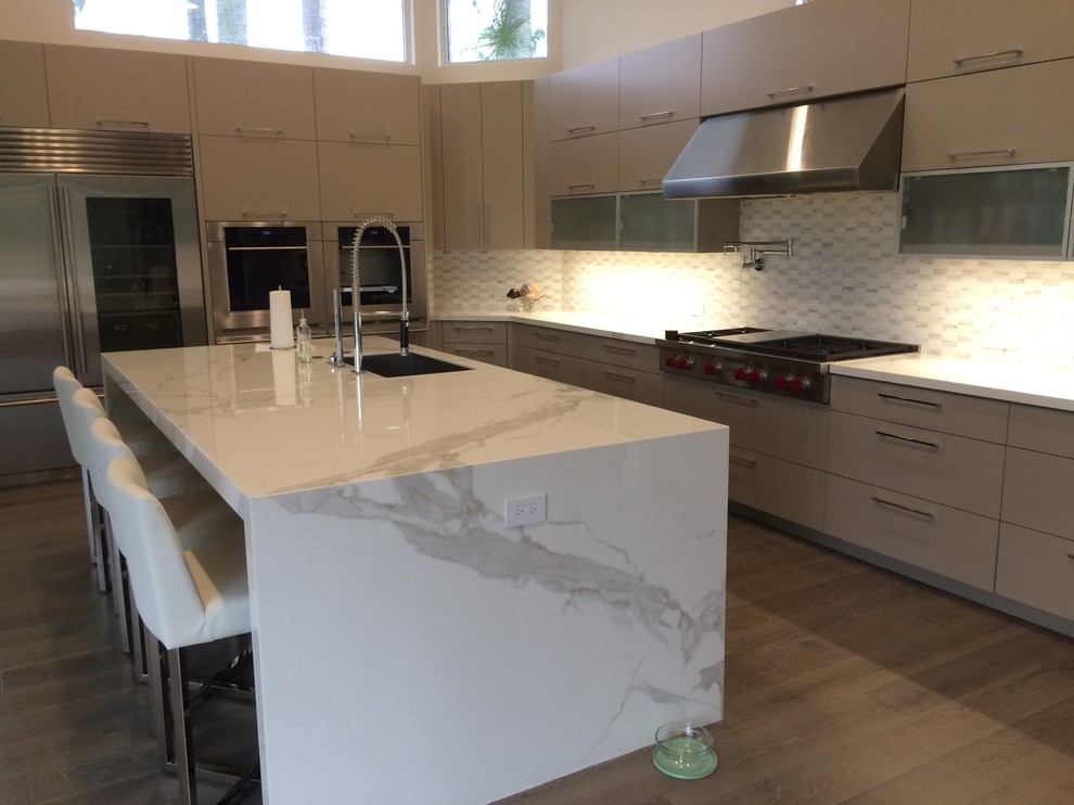 Design ideas for a large modern l-shaped eat-in kitchen in Miami with an undermount sink, flat-panel cabinets, grey cabinets, marble benchtops, grey splashback, stone tile splashback, stainless steel appliances, medium hardwood floors and with island.
