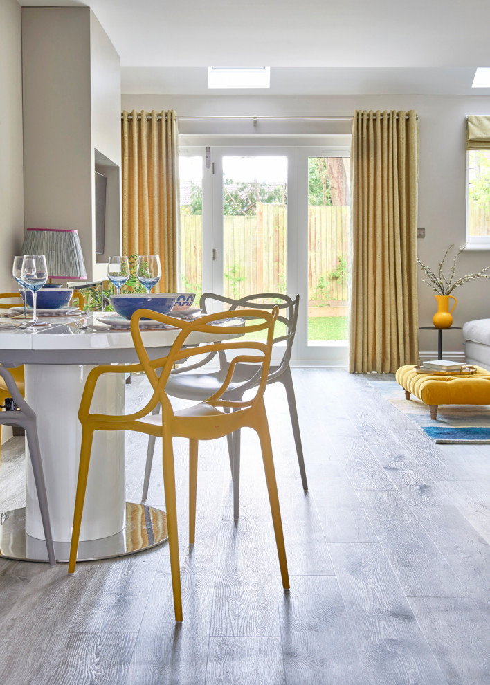 This is an example of a mid-sized contemporary open plan dining in Essex with grey walls, vinyl floors, a hanging fireplace, a wood fireplace surround and grey floor.