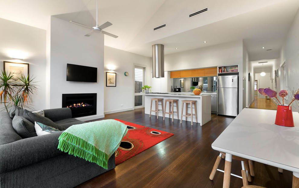 Inspiration for a mid-sized modern open concept living room in Melbourne with white walls, medium hardwood floors, a standard fireplace, a metal fireplace surround and a wall-mounted tv.