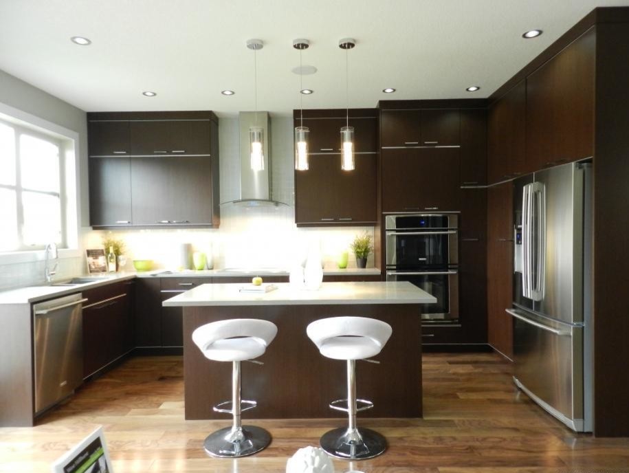 Design ideas for a mid-sized contemporary u-shaped kitchen in Calgary with an undermount sink, flat-panel cabinets, dark wood cabinets, quartz benchtops, white splashback, glass tile splashback, stainless steel appliances, medium hardwood floors and with island.