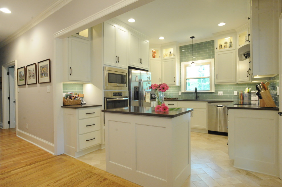 Transitional u-shaped travertine floor kitchen photo in Atlanta with a single-bowl sink, recessed-panel cabinets, white cabinets, quartz countertops, green backsplash, glass tile backsplash, stainless steel appliances and an island