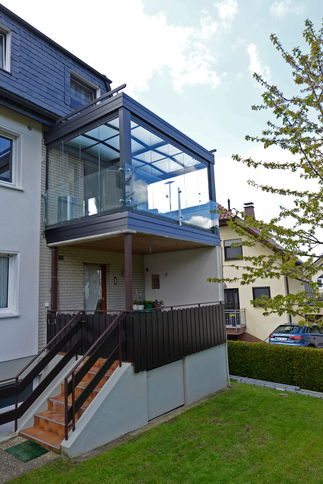 Mittelgroßer Moderner Wintergarten mit dunklem Holzboden, Kaminofen, Glasdecke und braunem Boden in Dortmund