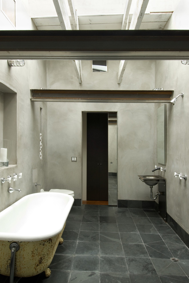 This is an example of a country bathroom in San Francisco with a claw-foot tub and slate floors.