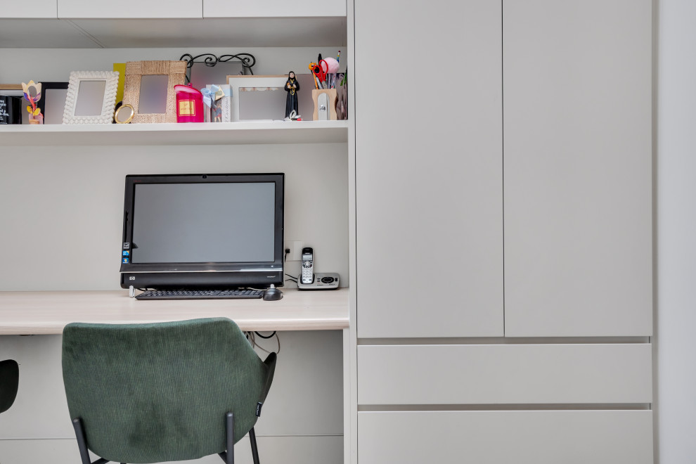 Esempio di un piccolo studio minimal con pareti bianche, scrivania incassata e pavimento grigio