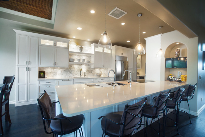 Inspiration for a large transitional galley dark wood floor and brown floor eat-in kitchen remodel in Denver with an undermount sink, shaker cabinets, white cabinets, gray backsplash, stone tile backsplash, stainless steel appliances and a peninsula