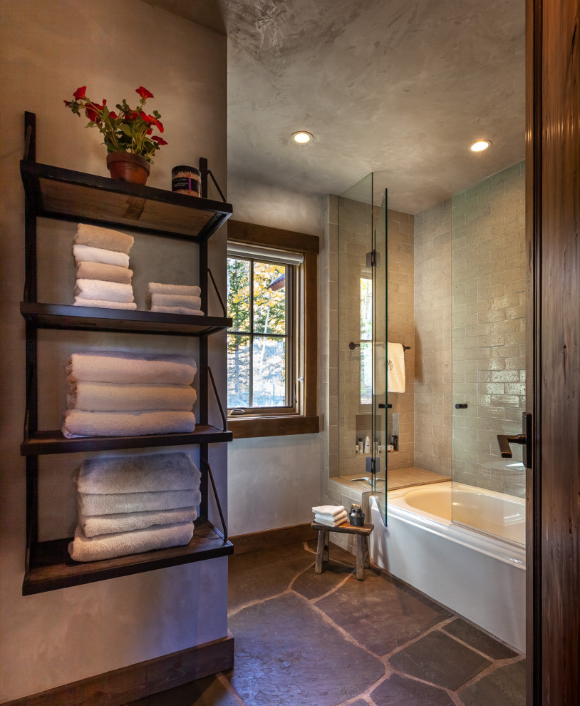 This is an example of a mid-sized country 3/4 bathroom in Denver with an alcove tub, a shower/bathtub combo, gray tile, grey walls, grey floor, slate floors and a hinged shower door.