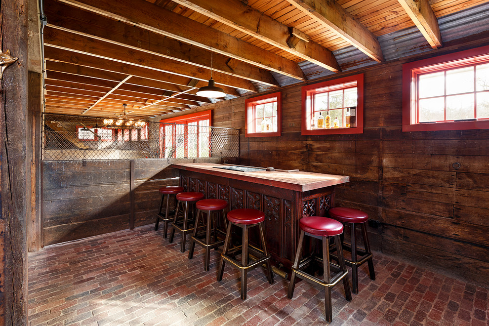 Mid-sized country galley seated home bar in Boston with dark wood cabinets, wood benchtops, brick floors and red floor.