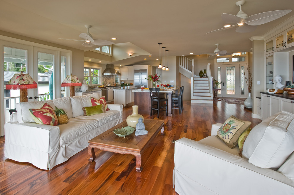 Tropical open concept family room in Hawaii with beige walls, medium hardwood floors and brown floor.