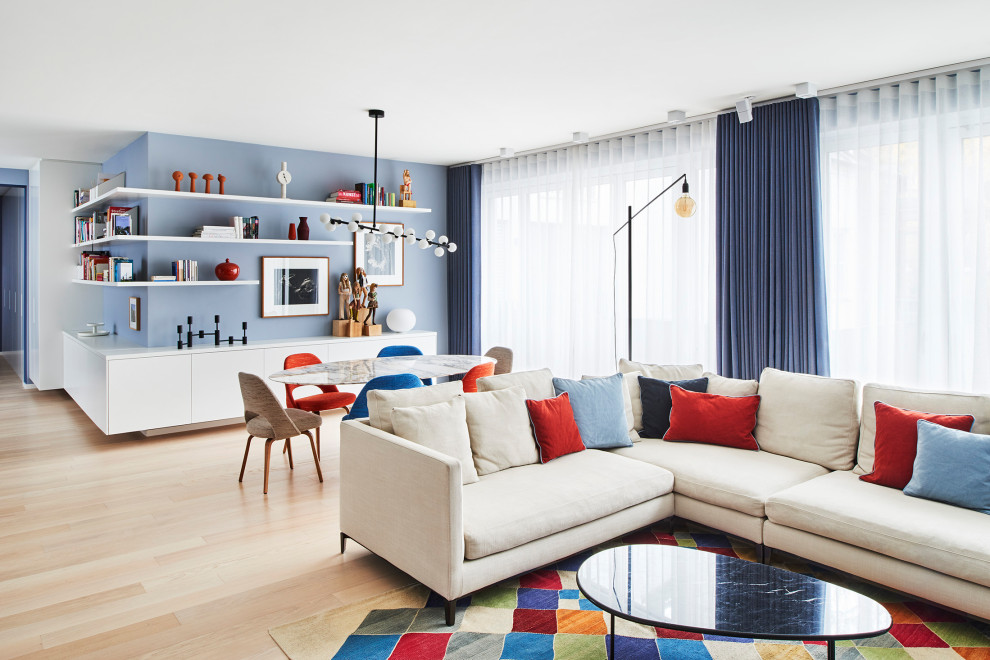 This is an example of a midcentury grey and white open plan living room in Berlin with blue walls, light hardwood flooring, a wall mounted tv and beige floors.