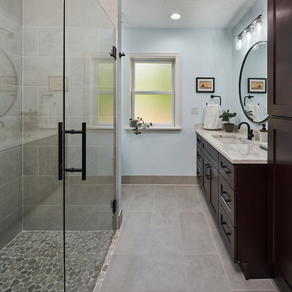Inspiration for a mid-sized traditional 3/4 bathroom in Portland with shaker cabinets, brown cabinets, a curbless shower, gray tile, porcelain tile, blue walls, porcelain floors, an undermount sink, engineered quartz benchtops, grey floor, a hinged shower door, beige benchtops, a niche, a single vanity and a built-in vanity.