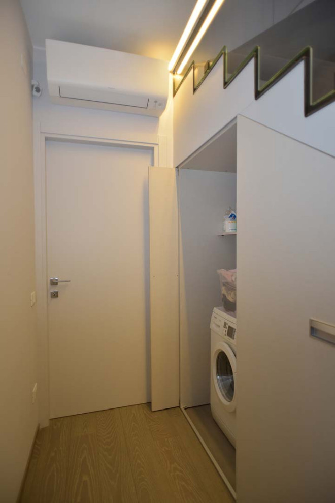 Exempel på en mellanstor modern tvättstuga, med vita väggar, mellanmörkt trägolv och brunt golv