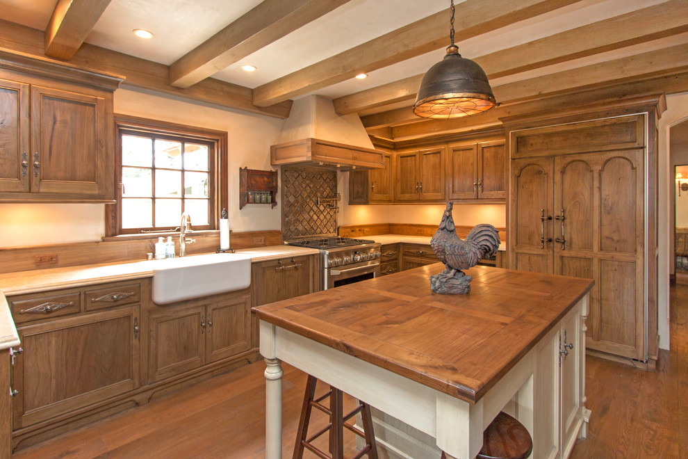 Mid-sized arts and crafts u-shaped medium tone wood floor and brown floor open concept kitchen photo with a farmhouse sink, recessed-panel cabinets, medium tone wood cabinets, paneled appliances, an island, brown backsplash, stone tile backsplash and beige countertops