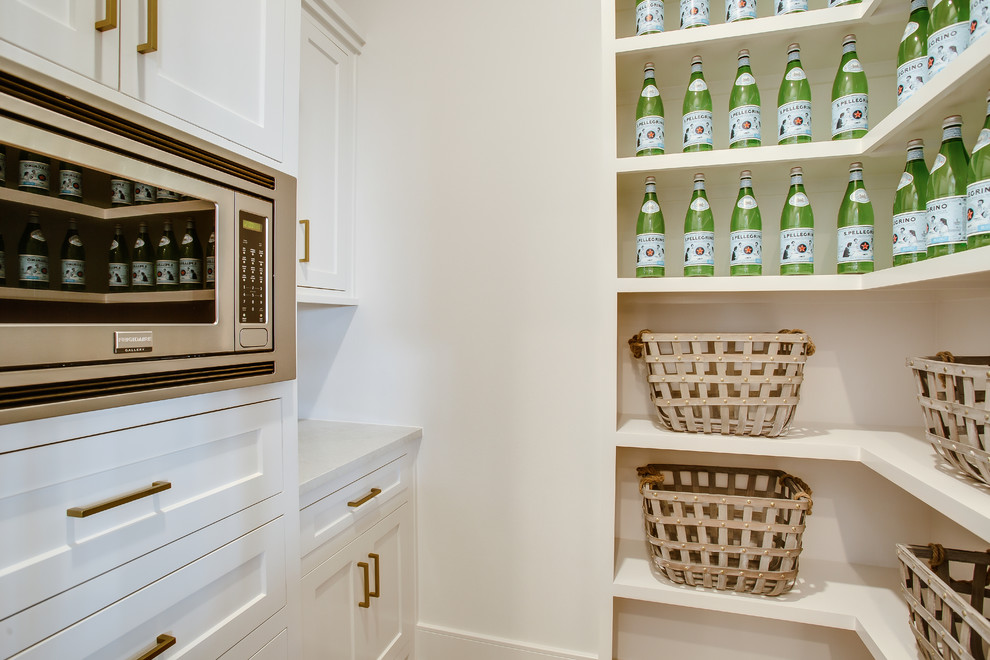 Mid-sized transitional l-shaped medium tone wood floor and brown floor kitchen pantry photo in Austin with a farmhouse sink, shaker cabinets, white cabinets, marble countertops, white backsplash, stainless steel appliances, an island and white countertops