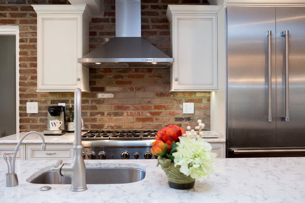 Inspiration for a large transitional medium tone wood floor eat-in kitchen remodel with an undermount sink, recessed-panel cabinets, black cabinets, quartz countertops, brick backsplash, stainless steel appliances and an island