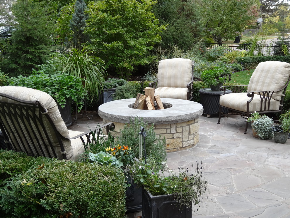 Photo of a mid-sized transitional backyard partial sun formal garden for fall in Omaha with natural stone pavers and a fire feature.