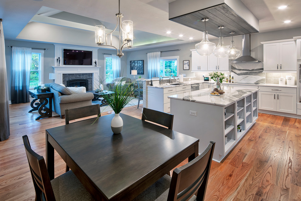 Example of a minimalist l-shaped medium tone wood floor open concept kitchen design in New York with an undermount sink, recessed-panel cabinets, white cabinets, quartz countertops, gray backsplash, porcelain backsplash, stainless steel appliances, an island and gray countertops