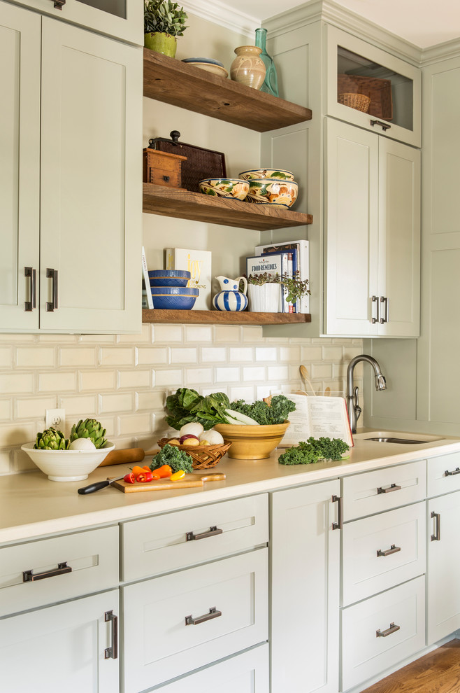This is an example of a mid-sized eclectic galley eat-in kitchen in Little Rock with a farmhouse sink, shaker cabinets, grey cabinets, quartzite benchtops, beige splashback, stainless steel appliances, medium hardwood floors, no island and subway tile splashback.
