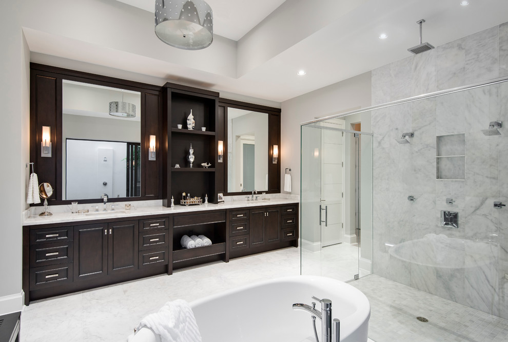 Photo of a large transitional master bathroom in Miami with recessed-panel cabinets, dark wood cabinets, a freestanding tub, a curbless shower, grey walls, marble floors, an undermount sink and marble benchtops.