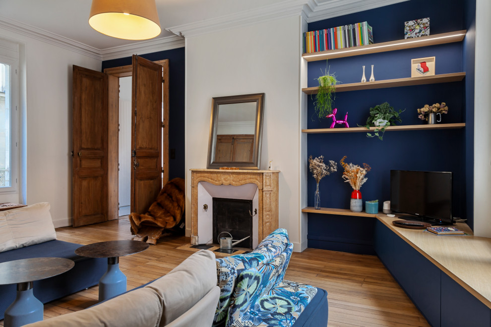 Exemple d'un salon chic de taille moyenne et ouvert avec un mur bleu, parquet clair et un manteau de cheminée en pierre.