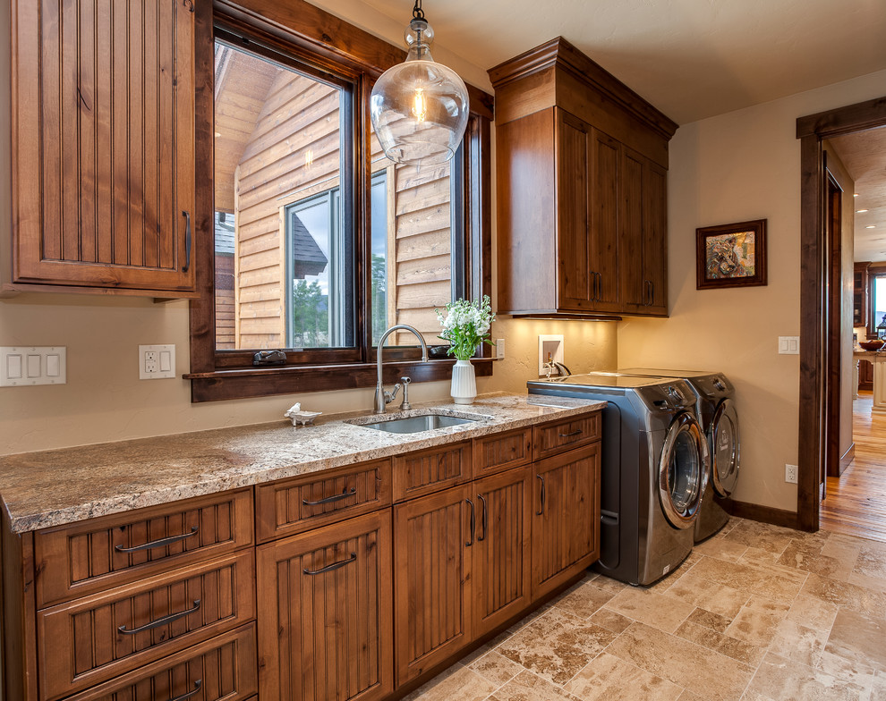 Large traditional galley utility room in Denver with an undermount sink, beaded inset cabinets, medium wood cabinets, granite benchtops, beige walls, porcelain floors, a side-by-side washer and dryer and beige floor.