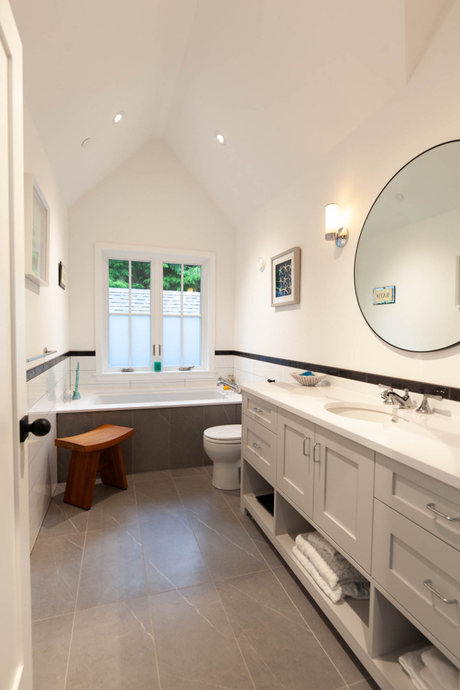 This is an example of a medium sized country bathroom in Vancouver with shaker cabinets, grey cabinets, a submerged bath, a built-in shower, all types of toilet, black and white tiles, porcelain tiles, white walls, porcelain flooring, a submerged sink, engineered stone worktops, green floors, a hinged door, white worktops, a single sink, a built in vanity unit and a vaulted ceiling.