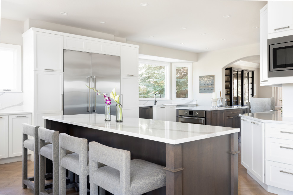 Enclosed kitchen - large transitional l-shaped light wood floor enclosed kitchen idea in Denver with a double-bowl sink, shaker cabinets, gray cabinets, quartz countertops, white backsplash, quartz backsplash, stainless steel appliances, two islands and white countertops