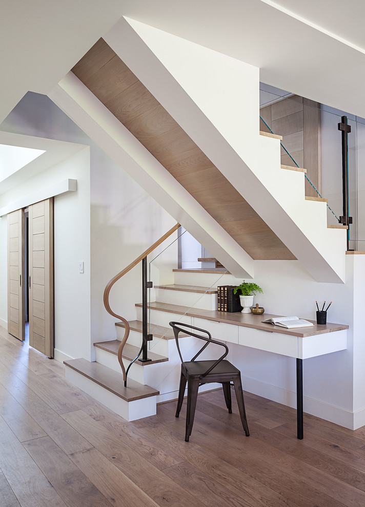 This is an example of an expansive contemporary wood u-shaped staircase in San Francisco with painted wood risers and glass railing.