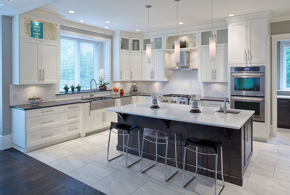 Inspiration for a large transitional l-shaped eat-in kitchen in Vancouver with a double-bowl sink, shaker cabinets, white cabinets, solid surface benchtops, white splashback, ceramic splashback, stainless steel appliances, ceramic floors and with island.