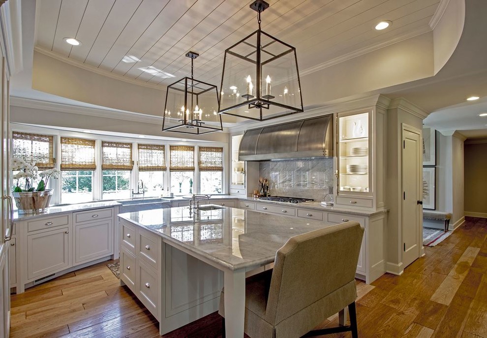 Enclosed kitchen - large transitional l-shaped light wood floor and brown floor enclosed kitchen idea in Austin with a farmhouse sink, recessed-panel cabinets, white cabinets, quartzite countertops, gray backsplash, stone slab backsplash, stainless steel appliances and an island