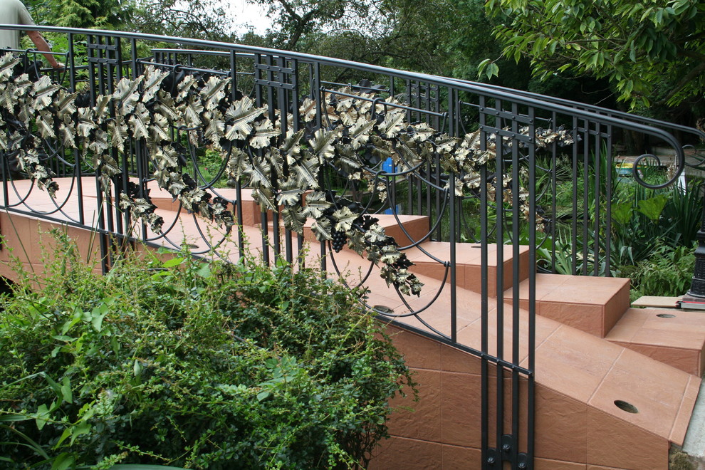 Стильный дизайн: солнечный, весенний регулярный сад среднего размера на заднем дворе в стиле фьюжн с забором, хорошей освещенностью, покрытием из каменной брусчатки и с металлическим забором - последний тренд