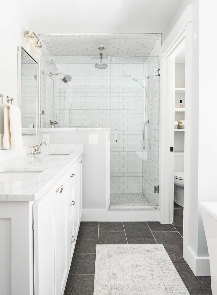 Inspiration for a mid-sized transitional master bathroom in Portland Maine with shaker cabinets, white cabinets, a freestanding tub, an open shower, white tile, subway tile, grey walls, slate floors, an undermount sink, marble benchtops, grey floor and a hinged shower door.