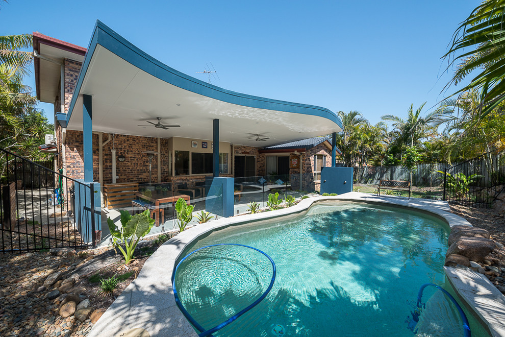 Mid-sized modern backyard kidney-shaped natural pool in Brisbane with natural stone pavers.