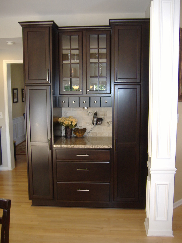 Inspiration for a mid-sized transitional u-shaped light wood floor eat-in kitchen remodel in Indianapolis with an undermount sink, flat-panel cabinets, dark wood cabinets, granite countertops, stainless steel appliances, beige backsplash and ceramic backsplash