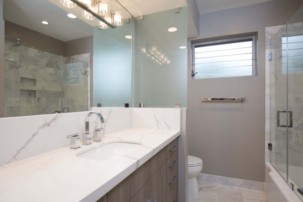 Design ideas for a small contemporary master bathroom in Miami with flat-panel cabinets, grey cabinets, an alcove tub, a shower/bathtub combo, a two-piece toilet, gray tile, marble, grey walls, marble floors, an undermount sink, engineered quartz benchtops, grey floor and a hinged shower door.