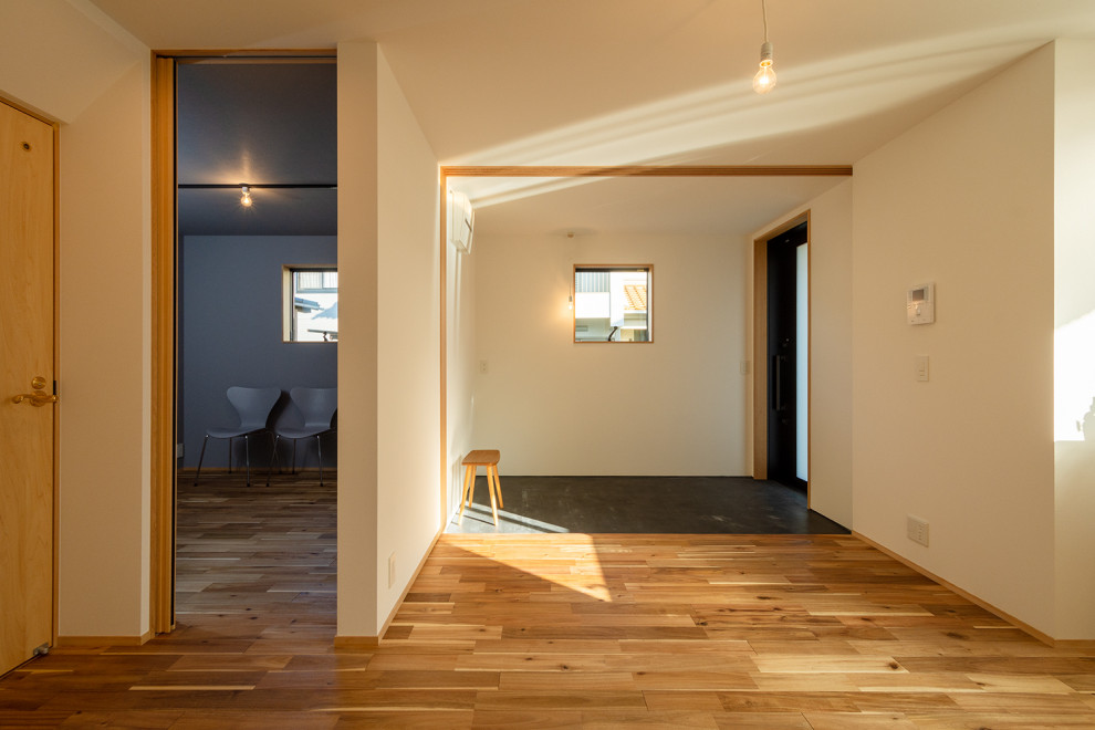 Réalisation d'une entrée nordique de taille moyenne avec un couloir, un mur blanc, un sol en bois brun, une porte coulissante, une porte noire, un sol marron, un plafond en papier peint et du papier peint.
