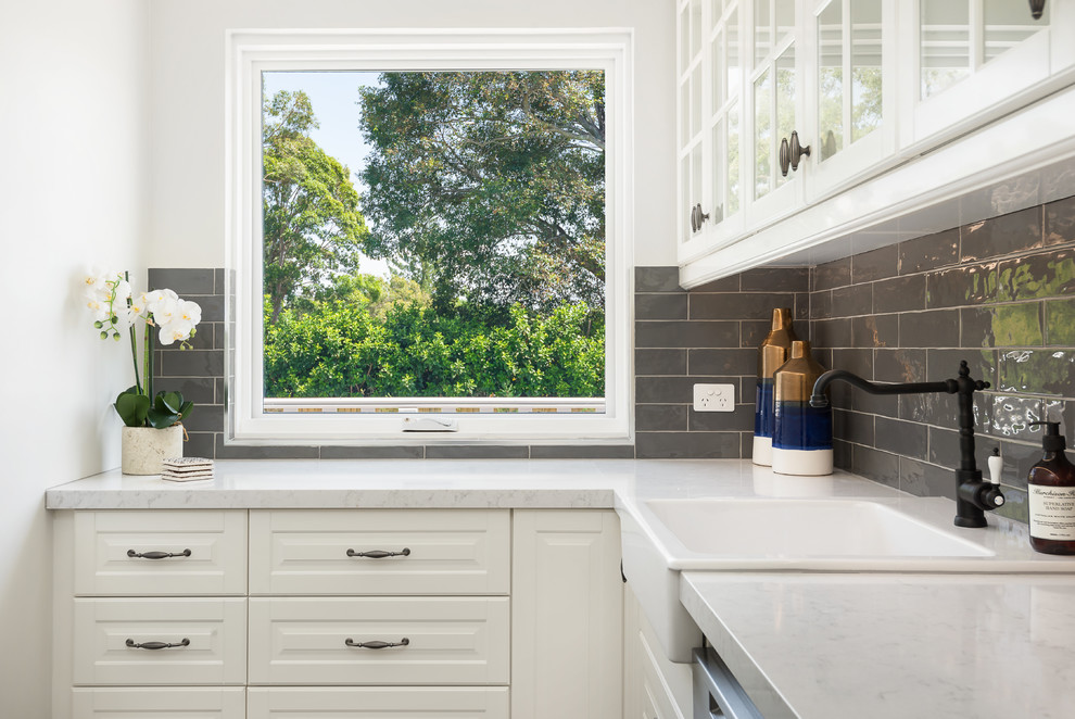 Large beach style l-shaped dedicated laundry room in Sydney with a farmhouse sink, shaker cabinets, white cabinets, marble benchtops, white walls and white benchtop.