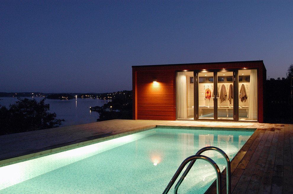Design ideas for a mid-sized contemporary backyard rectangular pool in Stockholm with a pool house and decking.