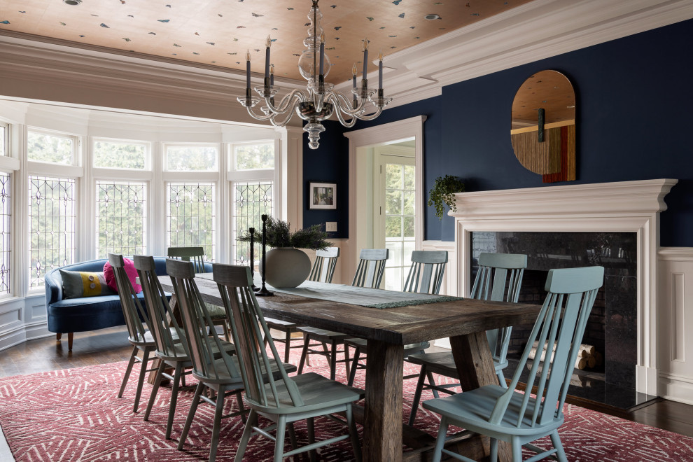 Cette photo montre une grande salle à manger éclectique avec un mur bleu, parquet foncé, une cheminée standard, un manteau de cheminée en pierre, un sol marron, un plafond en papier peint et du lambris.