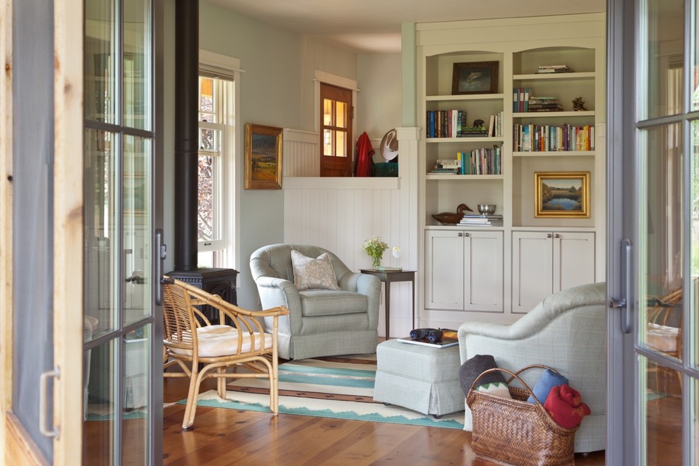 Inspiration for a mid-sized country open concept living room in Other with a library, blue walls, medium hardwood floors, a wood stove, a metal fireplace surround, no tv and brown floor.