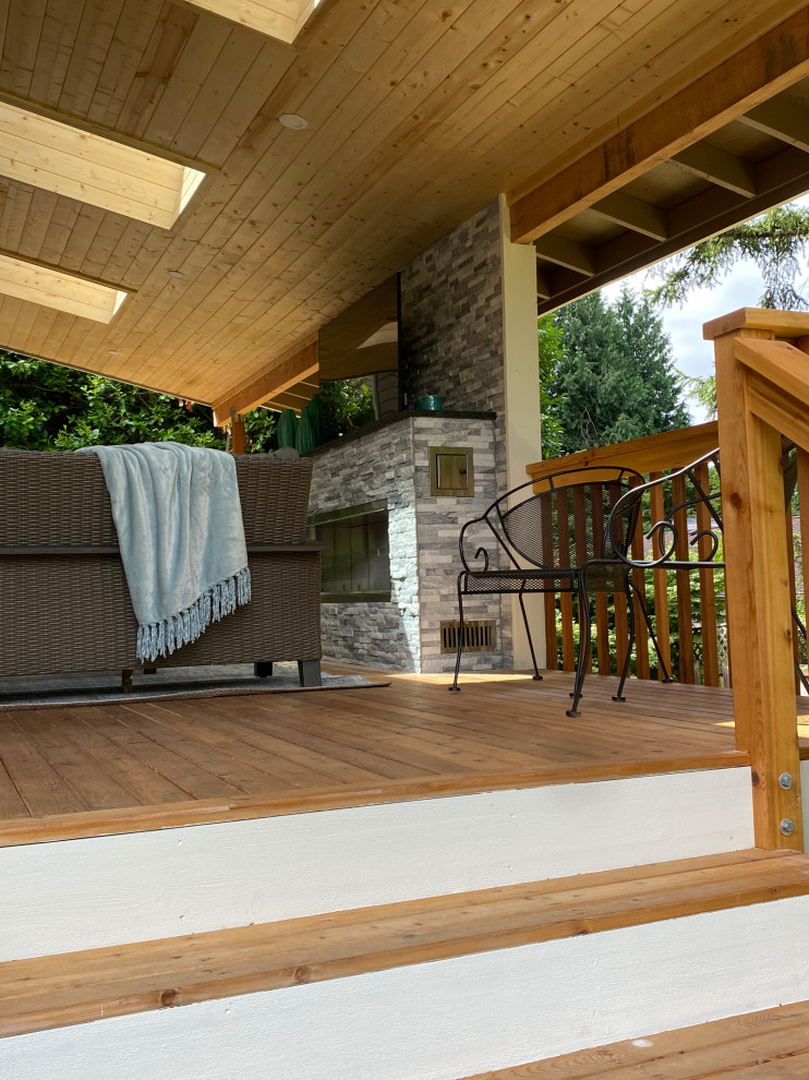 This is an example of a large classic back wood railing terrace with a fireplace and a roof extension.