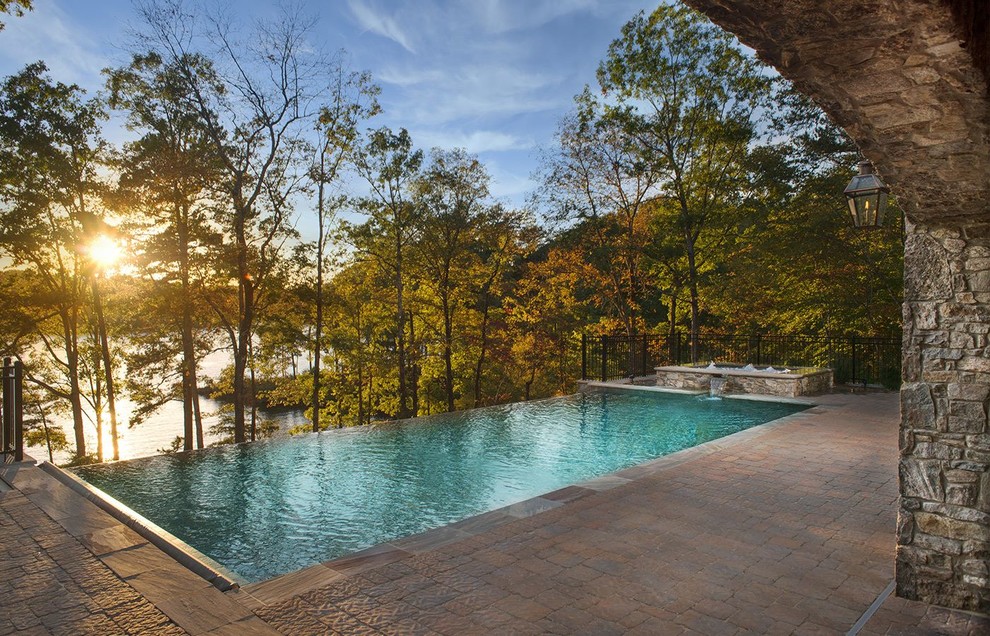 Mid-sized tropical backyard rectangular infinity pool in Other with a hot tub and concrete pavers.