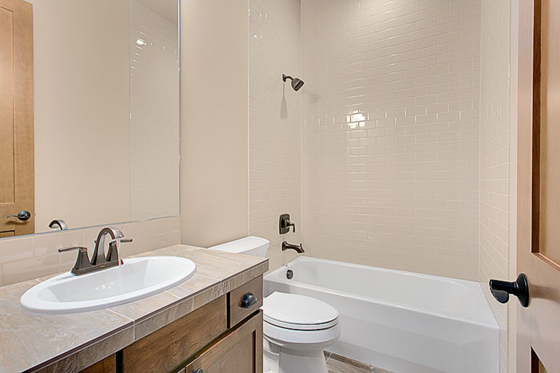 Inspiration for a mid-sized arts and crafts 3/4 bathroom in Seattle with recessed-panel cabinets, dark wood cabinets, an alcove tub, a shower/bathtub combo, a one-piece toilet, beige tile, subway tile, beige walls, porcelain floors, a drop-in sink and tile benchtops.