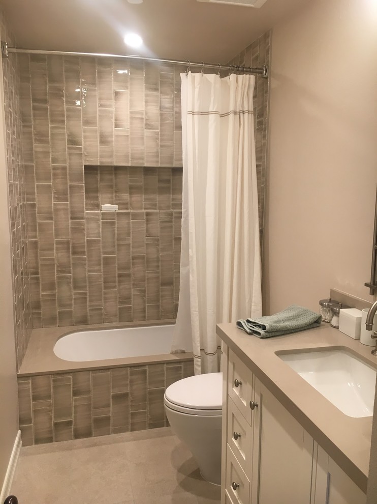 This is an example of a small modern kids bathroom in Los Angeles with shaker cabinets, beige cabinets, an undermount tub, a shower/bathtub combo, a one-piece toilet, gray tile, glass tile, grey walls, porcelain floors, an undermount sink, engineered quartz benchtops, grey floor and a shower curtain.