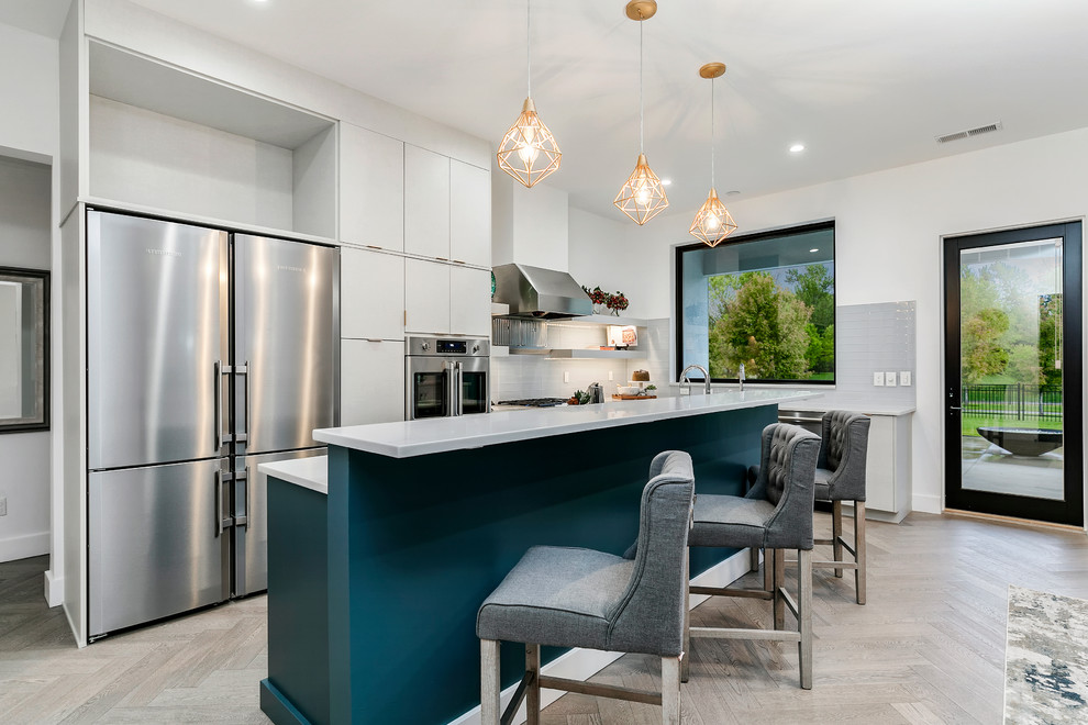 Large contemporary u-shaped eat-in kitchen in Boise with flat-panel cabinets, white cabinets, quartz benchtops, grey splashback, glass tile splashback, stainless steel appliances, light hardwood floors, with island, beige floor, white benchtop and an undermount sink.