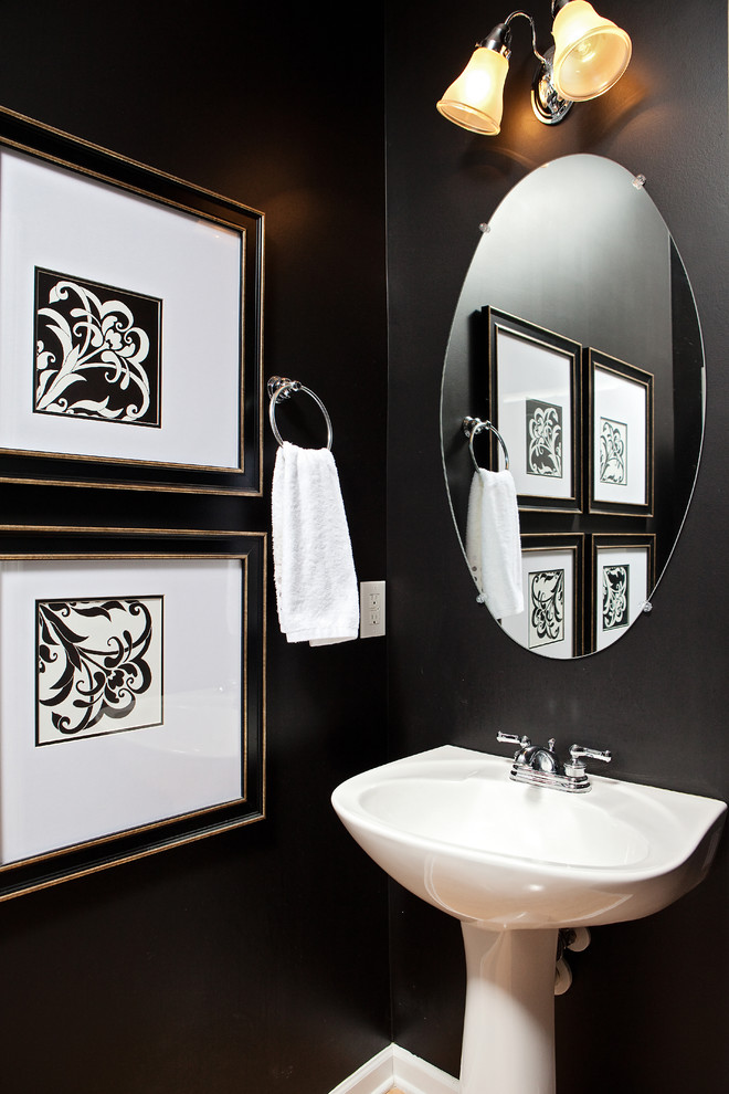 Mid-sized traditional powder room in Raleigh with a pedestal sink, black walls, light hardwood floors and brown floor.