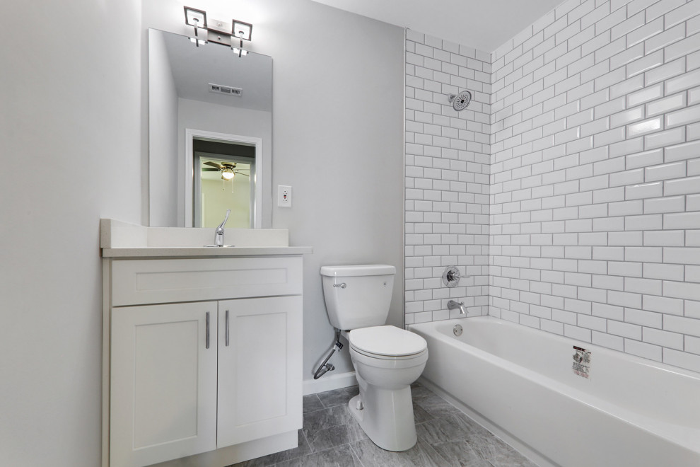 Cette image montre une salle de bain rustique avec un placard à porte shaker, des portes de placard blanches, une baignoire posée, un combiné douche/baignoire, WC à poser, un carrelage blanc, des carreaux de céramique, carreaux de ciment au sol, un lavabo encastré, un plan de toilette en quartz, un sol gris, un plan de toilette blanc, meuble simple vasque et meuble-lavabo encastré.