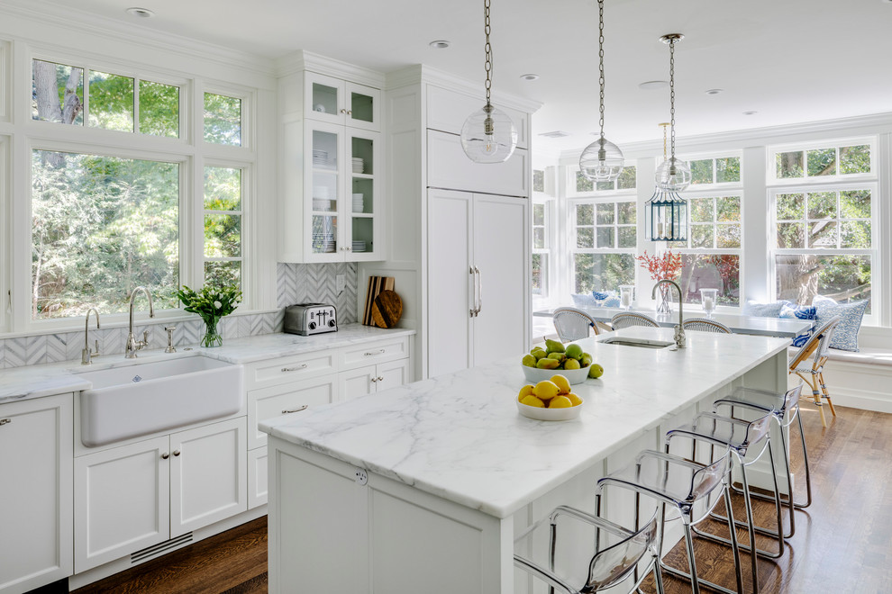 Eat-in kitchen - mid-sized transitional l-shaped medium tone wood floor and brown floor eat-in kitchen idea in Boston with recessed-panel cabinets, white cabinets, marble countertops, multicolored backsplash, stone tile backsplash and an island